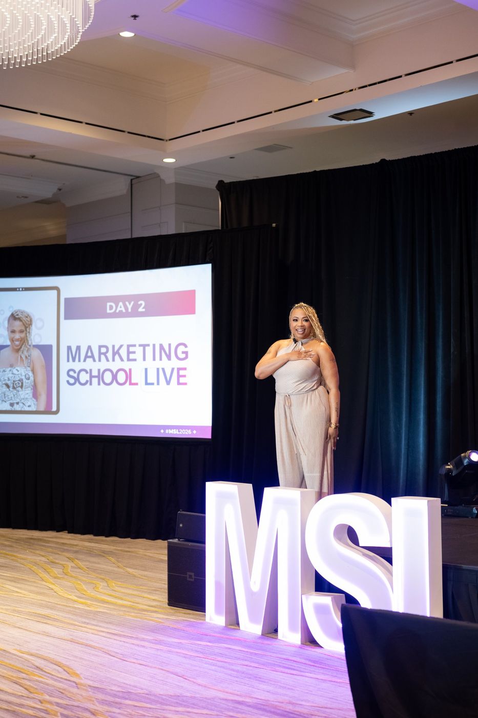 Aprille on the Marketing School LIVE stage with her hand on her heart